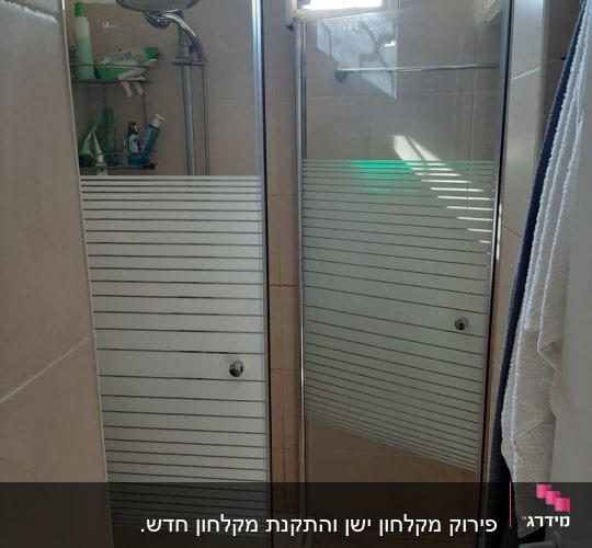 מקלחת עם דלת זכוכית, ראש מקלחת ומדף עם מוצרים